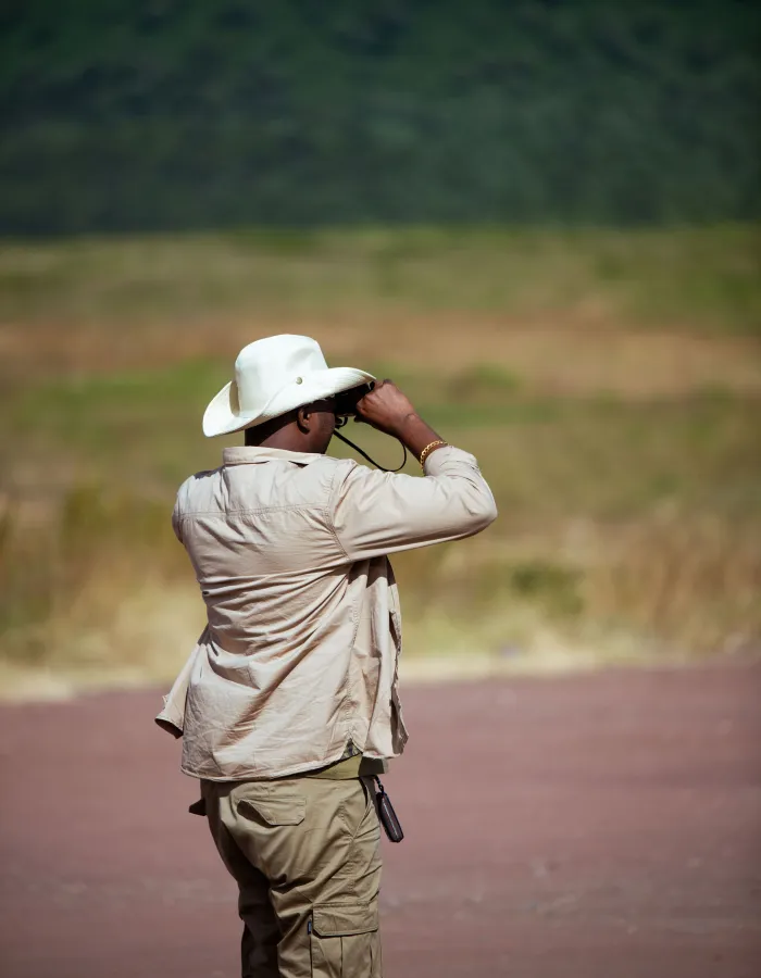 A TanzaLux guide scanning the plains with binoculars